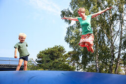 Mother and son (4 Jahre) jumping on a blue trampoline, Marielyst, Falster, Denmark