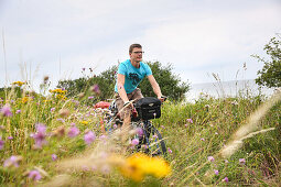 Fahrradfahrer fährt über einer Wiese, Marielyst, Falster, Dänemark