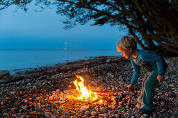 Boy at a campfire at Baltic Sea beach, Naesgaard, Falster, Denmark