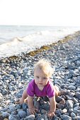 Mädchen (1 Jahr) krabbelt über Kieselstrand, Klintholm, Insel Mön, Dänemark