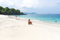 Frau sitzt am White Sand Beach, Padang Bai, Bali, Indonesien