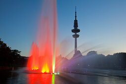 Illuminated water fountain in the park lake, television tower in the background, Planten un Blomen, Hamburg, Germany