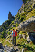Frau wandert auf Weg auf Felsturm zu, Trans-Lagorai, Lagorai-Höhenweg, Lagorai, Dolomiten, UNESCO Welterbe Dolomiten, Trentino, Italien