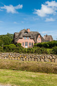 Thatched-roof house surrounded by natural stone wall, Sylt, Schleswig-Holstein, Germany
