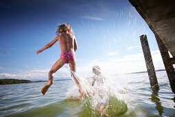 Two girls jumping into the water, lake Starnberg, Upper Bavaria, Bavaria, Germany