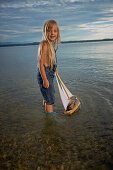 Girl with a toy sailboat in lake Starnberg, Upper Bavaria, Bavaria, Germany