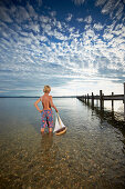 Boy with toy sail boat standing in lake Starnberg, Upper Bavaria, Bavaria, Germany