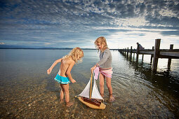 Zwei Mädchen mit einem Segelboot im Starnberger See, Oberbayern, Bayern, Deutschland