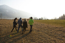 Young people crossing a meadow, Grosser Alpsee, Immenstadt, Bavaria, Germany