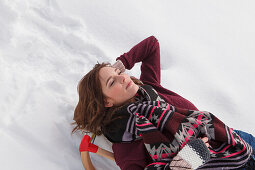 Junge Frau liegt auf einem Schlitten, Spitzingsee, Oberbayern, Bayern, Deutschland