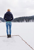 Young woman on a jetty at snow-covered lake Spitzingsee, Upper Bavaria, Germany