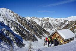 Several persons back-country skiing standing in front of alpine hut, Frauenwand, valley of Schmirn, Zillertal Alps, Tyrol, Austria