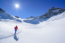 Woman back-country skiing ascending towards Col della Portiola, in the background Rocca Blancia, Valle di Stroppia, Valle Maira, Cottian Alps, Piedmont, Italy