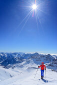 Woman back-country skiing ascending towards Monte Faraut, in background Tete de Moise and Monte Cervet, Monte Faraut, Valle Varaita, Cottian Alps, Piedmont, Italy