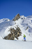 Woman back-country skiing ascending towards Monte Salza, spire in the background, Monte Salza, Valle Varaita, Cottian Alps, Piedmont, Italy
