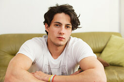 Young man sitting on the sofa, pensive