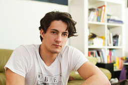 Young man sitting on the sofa, pensive