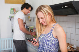 Young couple in the kitchen, woman on her mobile