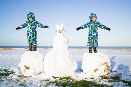 Boys playing on a huge snowball, Cuxhaven, North Sea, Lower Saxony, Germany