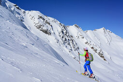 Woman back-country skiing ascending towards Punta San Matteo, Pizzo Tresero in background, Punta San Matteo, Val dei Forni, Ortler range, Lombardy, Italy