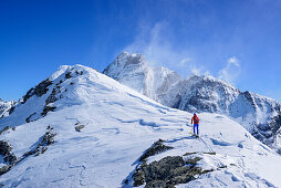 Woman back-country skiing ascending towards Punta Tre Chiosis, in the background Monte Viso, Punta Tre Chiosis, Valle Varaita, Cottian Alps, Piedmont, Italy