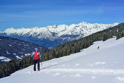 Woman back-country skiing ascending towards Gilfert, Karwendel range and valley of Inn in background, Gilfert, Tux Alps, Tyrol, Austria