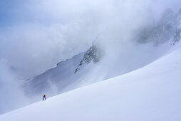 Frau auf Skitour steigt durch Wolkentreiben zum Grundschartner auf, Grundschartner, Zillergrund, Zillertaler Alpen, Tirol, Österreich