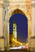 Illuminated Siegestor with view to Ludwigstrasse with church of St. Michael, Michaelskirche, Siegestor, Munich, Upper Bavaria, Bavaria, Germany