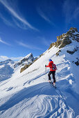 Woman back-country skiing ascending towards Monte Soubeyran, in background Tete Peymian, Punta della Reculaye and Aiguille de Barsin, Monte Soubeyran, Valle Maira, Cottian Alps, Piedmont, Italy