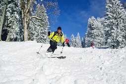 Zwei Personen auf Skitour fahren durch Winterwald ab, Sonntagshorn, Chiemgauer Alpen, Salzburg, Österreich