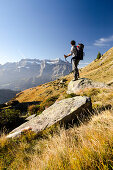 Ein jüngerer Wanderer steht in der Nähe der Mettmenalp auf einem Stein und betrachtet die Gipfel des Glärnisch Massivs, Glarner Alpen, Kanton Glarus, Schweiz