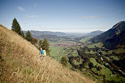 Junger Mann wandert einen Berg hinauf an einem sonnigen Tag, Oberstdorf, Bayern, Deutschland