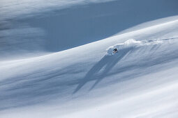 Young female freeskier riding through deep powder snow in the mountains, Pitztal, Tyrol, Austria