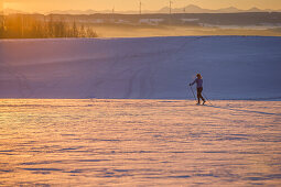 Junge Frau geht Langlaufen während eines Sonnenuntergangs, Allgäu, Bayern, Deutschland
