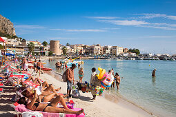 People relax at Mondello beach on a sunny Sunday morning as beach toy vendor strolls by, Mondello, near Palermo, Sicily, Italy