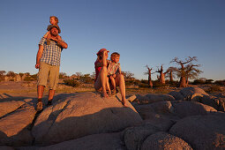 Familie betrachtet Aussicht im Sonnenuntergang, Kubu Island, Makgadikgadi Pans Nationalpark, Botswana