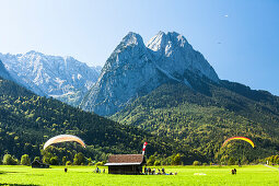 Gleitschirmflieger landen auf einer Wiese unter dem Waxenstein, Garmisch-Partenkirchen, Bayern, Deutschland