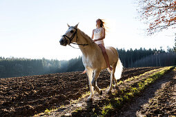 Mädchen reitet in weißem Kleidchen auf Pferd, Freising, Bayern, Deutschland