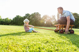 two-year-old girl pulling her father across the meadow, Speyer, Rheinland-Pfalz, Germany