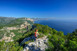 Frau wandert am Selvaggio Blu über Felsgrat mit Blick auf Mittelmeer, Selvaggio Blu, Nationalpark Golfo di Orosei e del Gennargentu, Sardinien, Italien