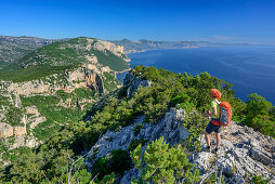 Frau wandert am Selvaggio Blu über Felsgrat mit Blick auf Mittelmeer, Selvaggio Blu, Nationalpark Golfo di Orosei e del Gennargentu, Sardinien, Italien