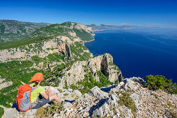 Frau sitzt am Selvaggio Blu und blickt auf Mittelmeer, Selvaggio Blu, Nationalpark Golfo di Orosei e del Gennargentu, Sardinien, Italien