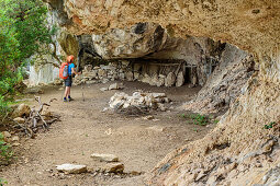 Woman hiking Selvaggio Blu crossing cliff with shepherds shelter, Selvaggio Blu, National Park of the Bay of Orosei and Gennargentu, Sardinia, Italy