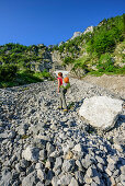 Woman ascending through scree to fixed rope route Pidinger Klett, Hochstaufen, Chiemgau Alps, Chiemgau, Upper Bavaria, Bavaria, Germany