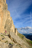 Woman hiking beneath rock face, Rotwand, Rosengarten, UNESCO world heritage Dolomites, Dolomites, Trentino, Italy