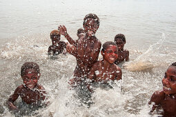 Cheerful children swim and splash in water, Kopar, East Sepik Province, Papua New Guinea, South Pacific