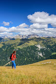 Woman hiking towards Sas Aut, Sella range in background, Sas Aut, Vallaccia range, Marmolada, Dolomites, UNESCO World Heritage Dolomites, Trentino, Italy