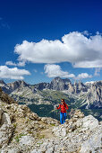 Woman hiking ascending towards Vallaccia, Rosengarten range in background, Vallaccia, Vallaccia range, Marmolada, Dolomites, UNESCO World Heritage Dolomites, Trentino, Italy