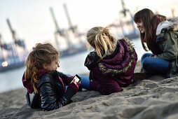3 girls viewing the port at the Elbe River beach, Oevelgoenne, Hamburg, Germany, Europe