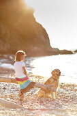 Six year old girl with labrador on pebble beach at Portoferraio, Elba, Tuscany, Italy